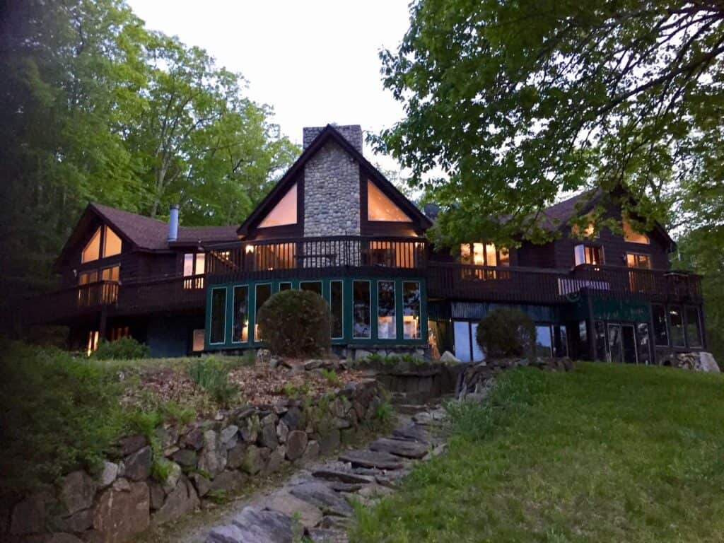 A very large tudor style hotel or house. The interior lights are on and there are trees around the building.