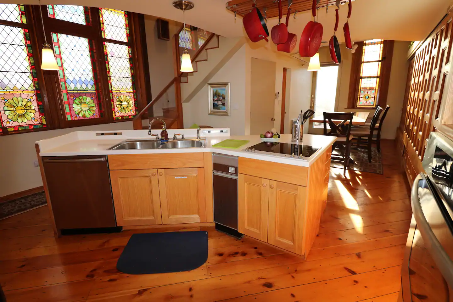 A kitchen with red pots hanging from ceiling