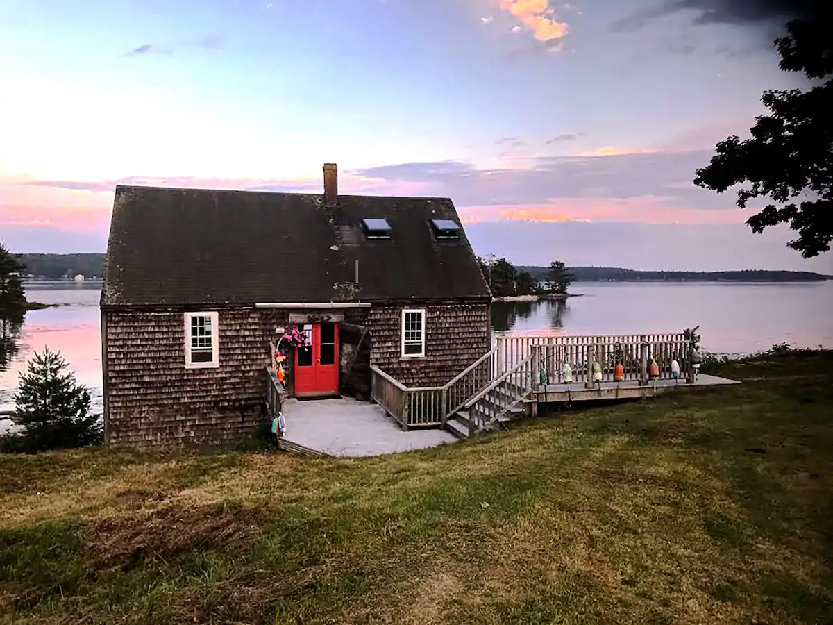 Grey cabin with steps next to a body of water