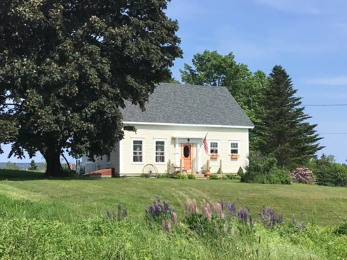 White house in a field surrounded by trees