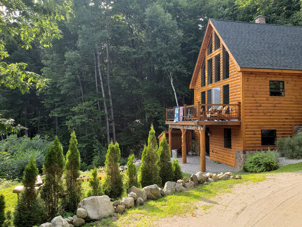 A chalet with a low rock wall and bushes out front