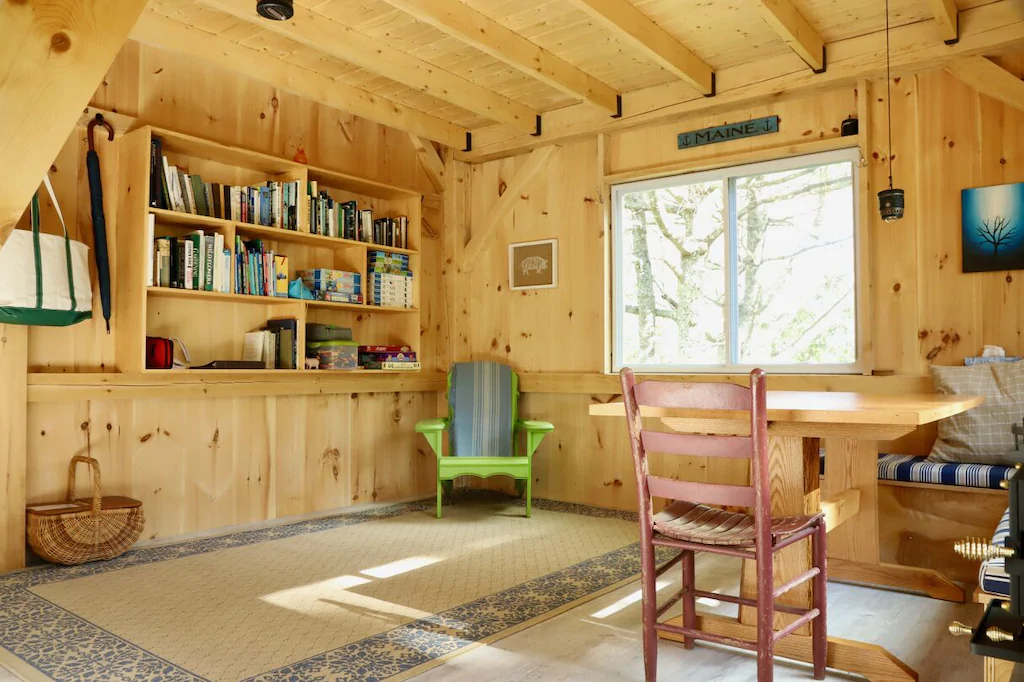 A paneled room with 2 chairs and a bookshelf with books