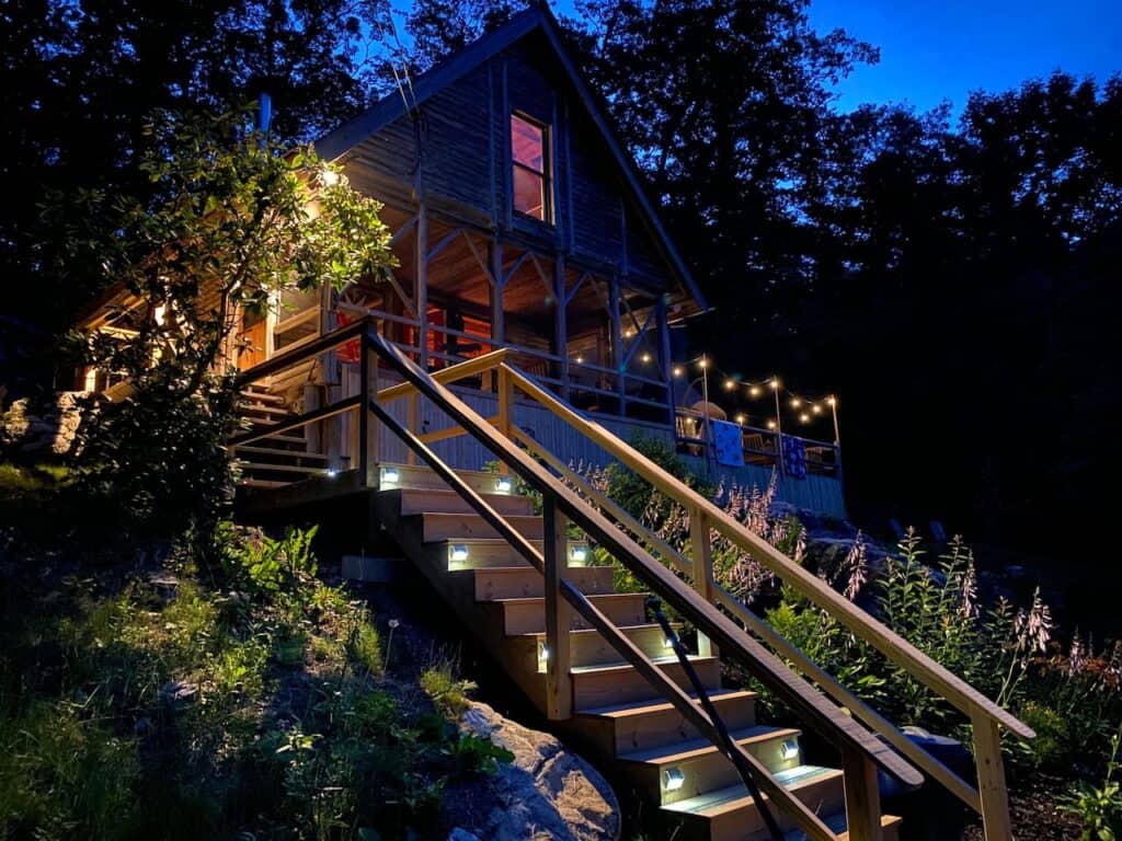 Wooden steps with lights leading up to a chalet at dusk