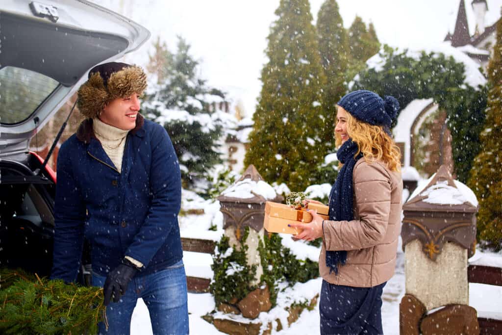 Couple smiling at each other outdoors as they pack a car.