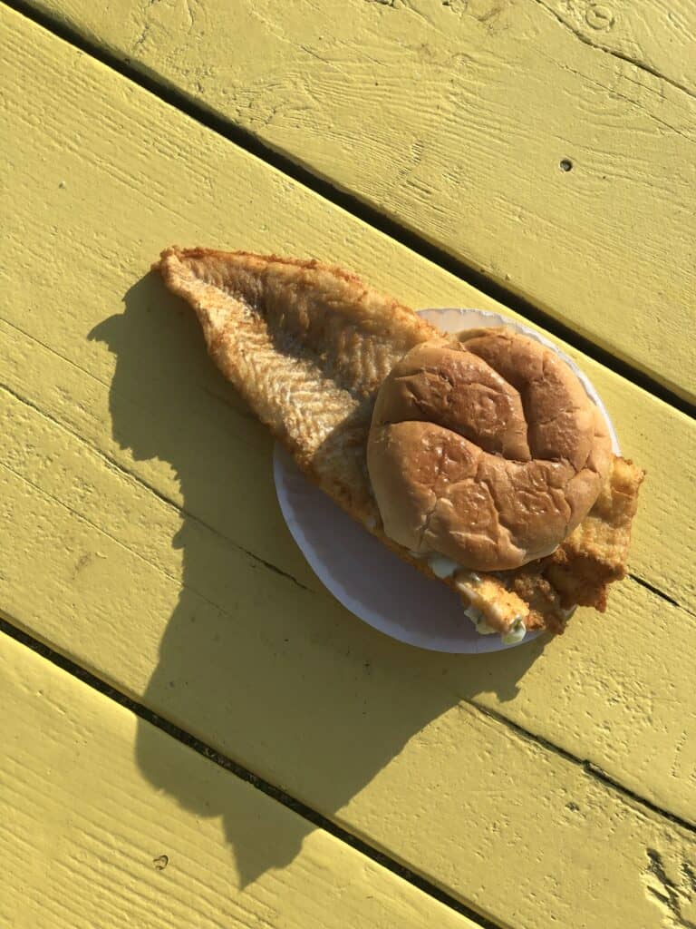 A sandwich with fish sitting on top of a wooden table at one of the top seafood restaurants in Maine