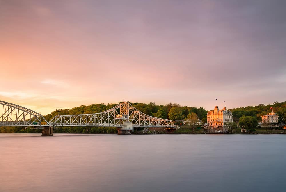 A bridge in the distance next to a body of water at sunset