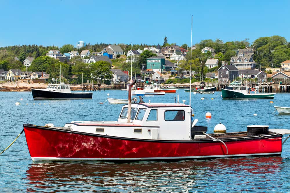 A red and white boat in the water with a town in the distance