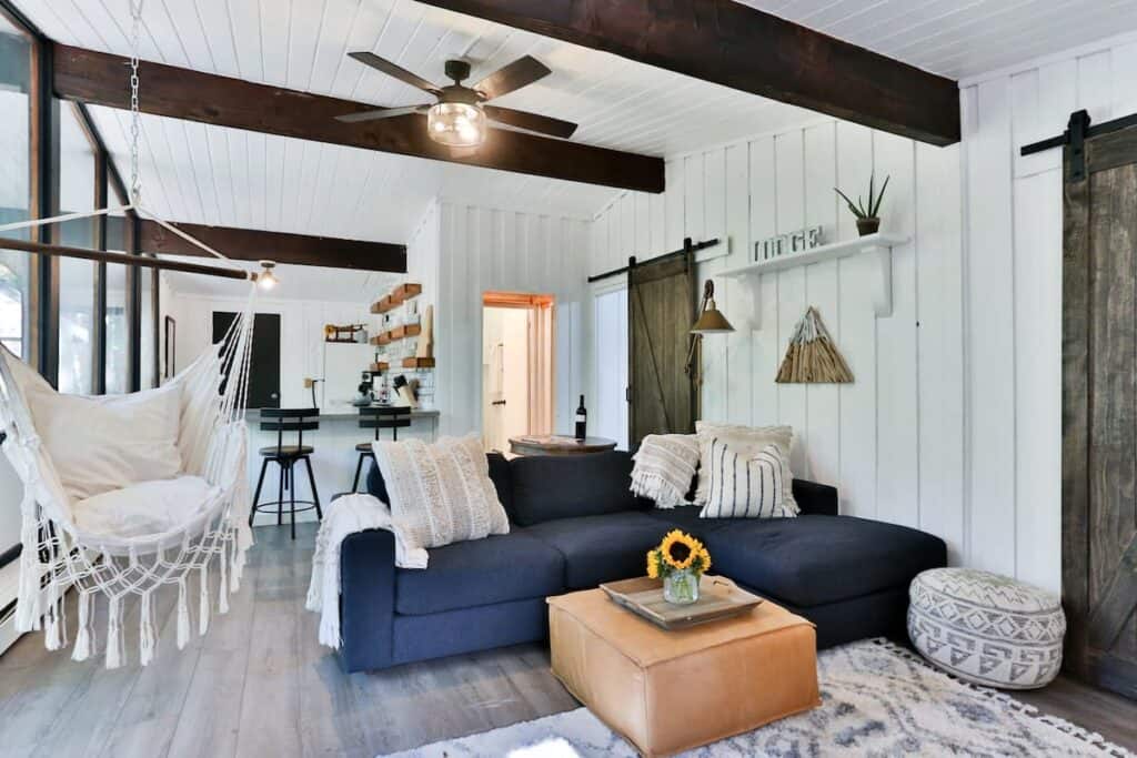 A living room with a royal blue sectional couch and barstools and a ceiling fan