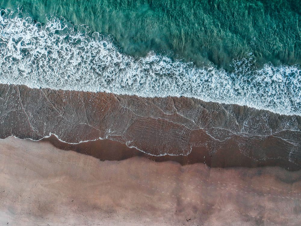Aerial shot of one of the best beaches in Rhode Island and green ocean tides crashing up against it