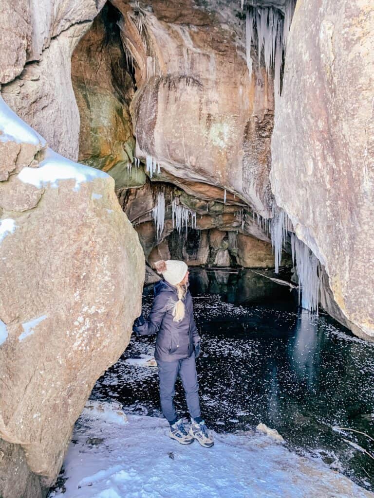Girl standing in a cave with water.