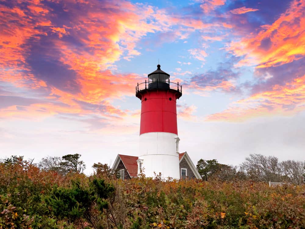 A lighthouse with a colorful sunset behind it