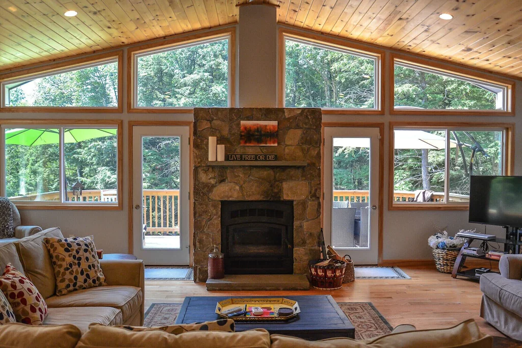 Interior of a chalet living room with windows and a stone fireplace