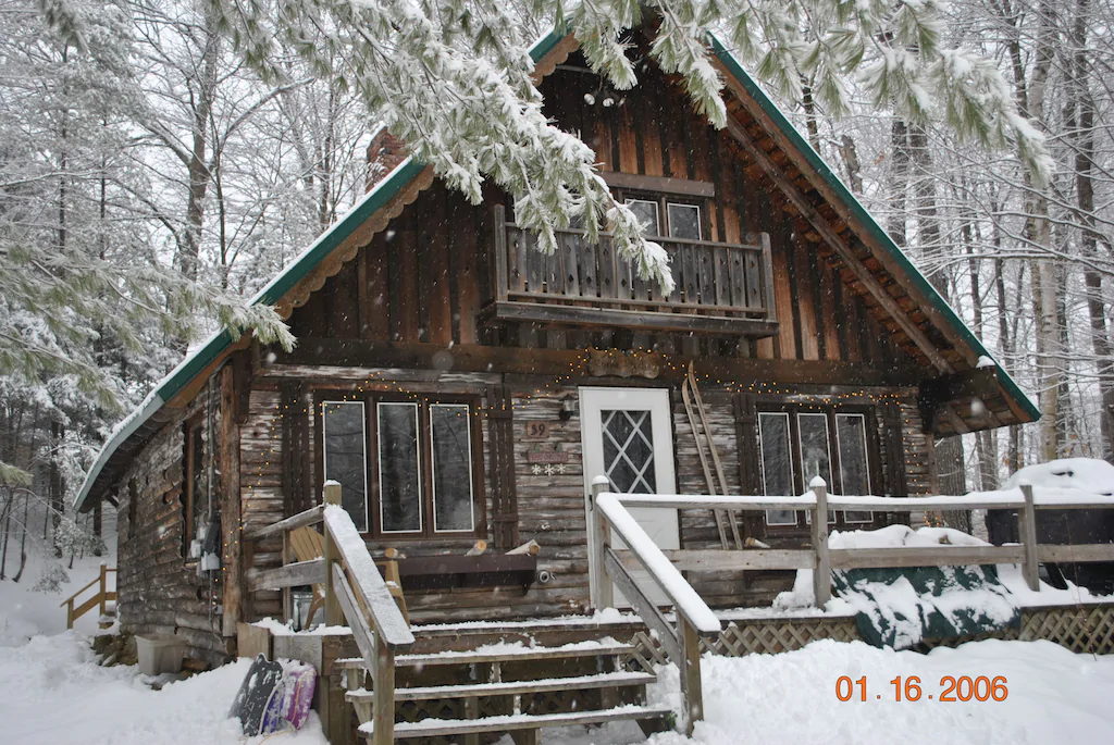 A chalet with front steps and a deck in the snowy woods