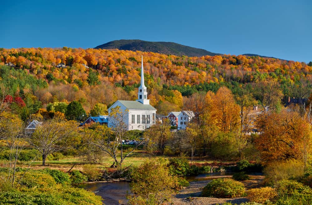 A white church surrounded by fall trees in the mountains