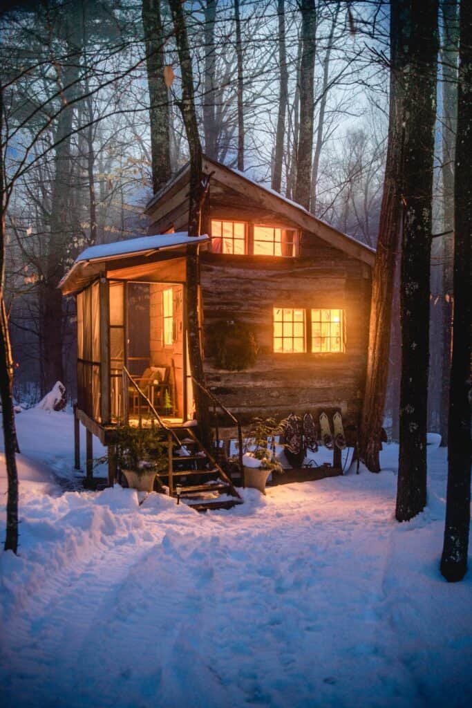 A house with interior lights on and snow covered ground