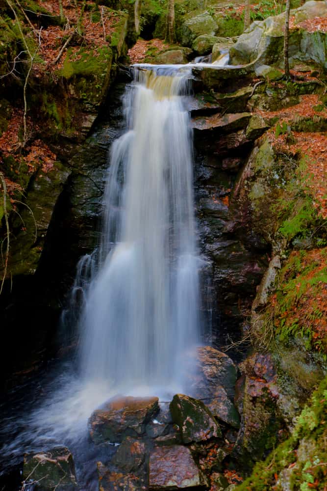 Waterfall cascading down rocks surrounded by fall moss.