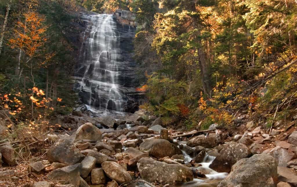 Water cascading down rocks leading to more rocks and water, surrounded by trees and fall colors.