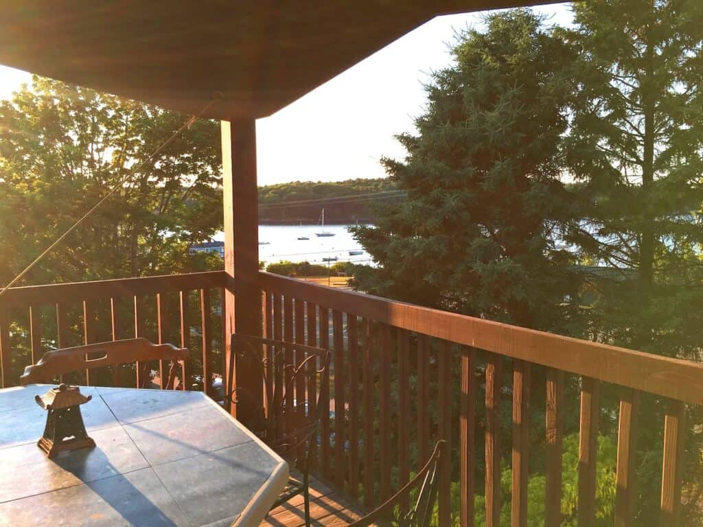 Wooden railing on porch with body of water in the distance