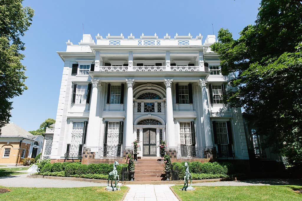 Looking up towards a white mansion with 4 columns and steps