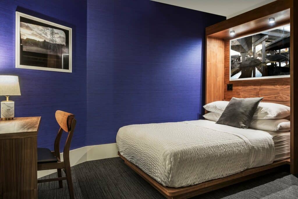 A bed with a white bedspread and royal blue wall