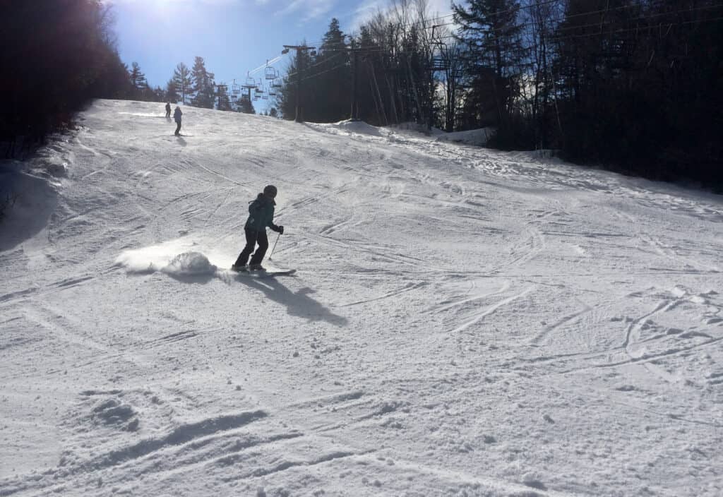 Skiiers skiing down a slope under a blue sky.