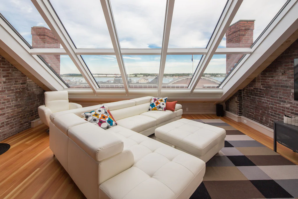 White sectional couch next to a wall of windows at a hip New England VRBO