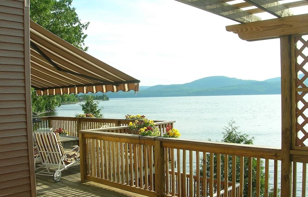 A wooden railing of a deck overlooking a body of water with a mountain in the distance