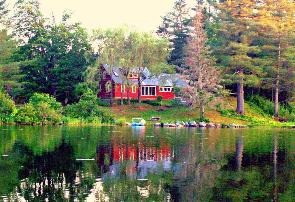 Red House among trees reflected in a body of water 