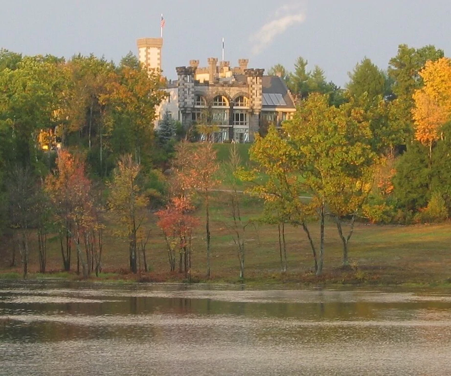 Body of water with trees and a mansion in the distance