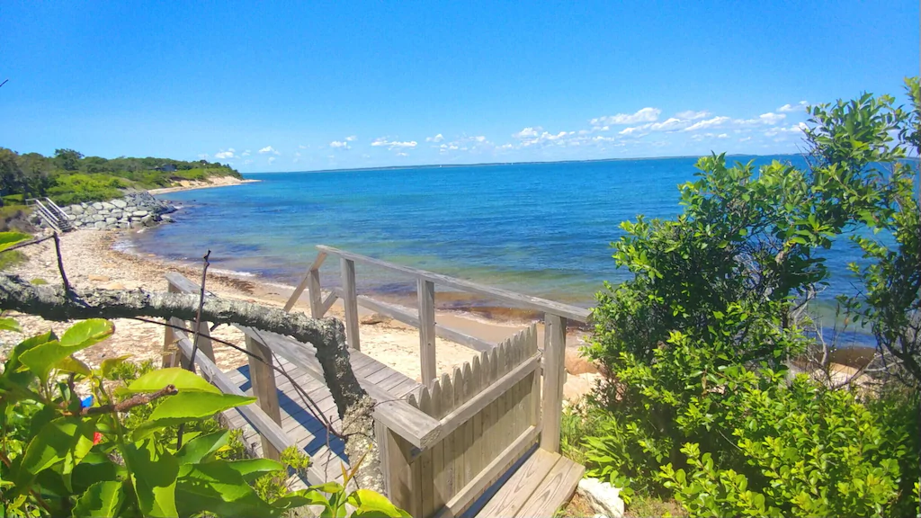 Deck with steps leading down to the beach and the blue ocean at a private beach VRBO on Martha's Vineyard