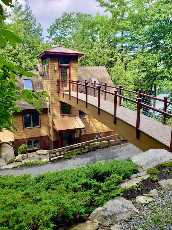 A wooden bridge leading to the 3rd story of a house in the woods