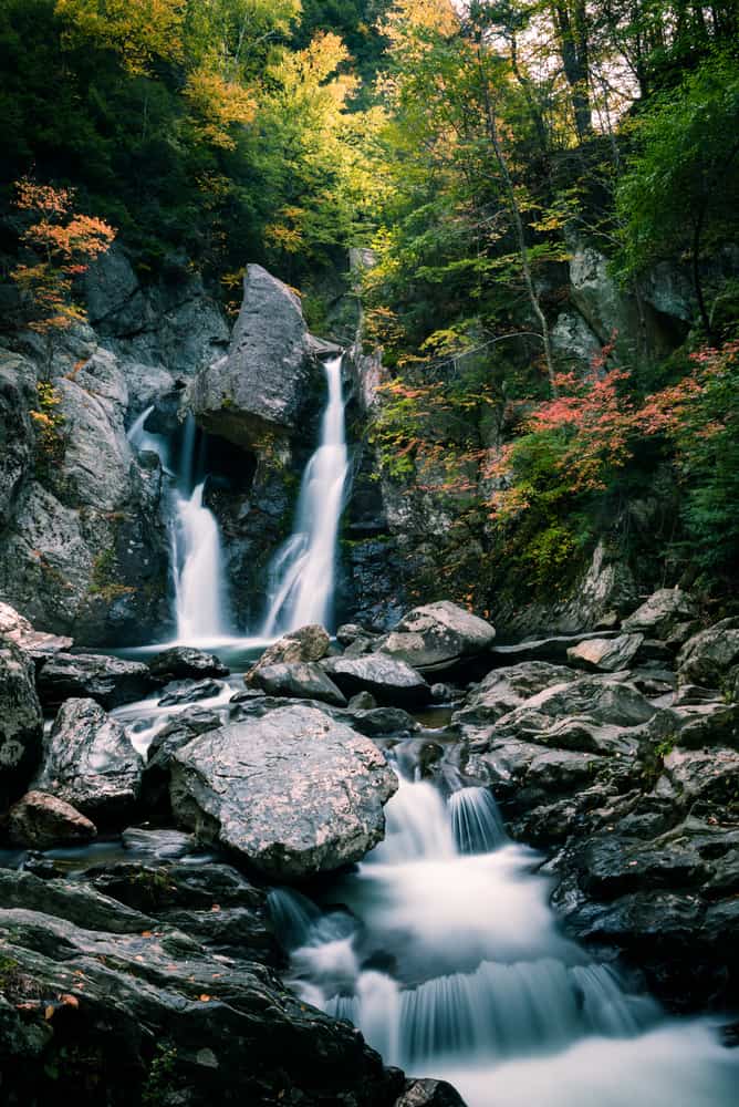 A twin waterfall cascading down onto many rocks 