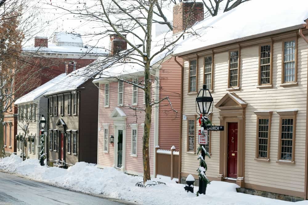 Snow-covered sidewalk in front of a row of two story houses