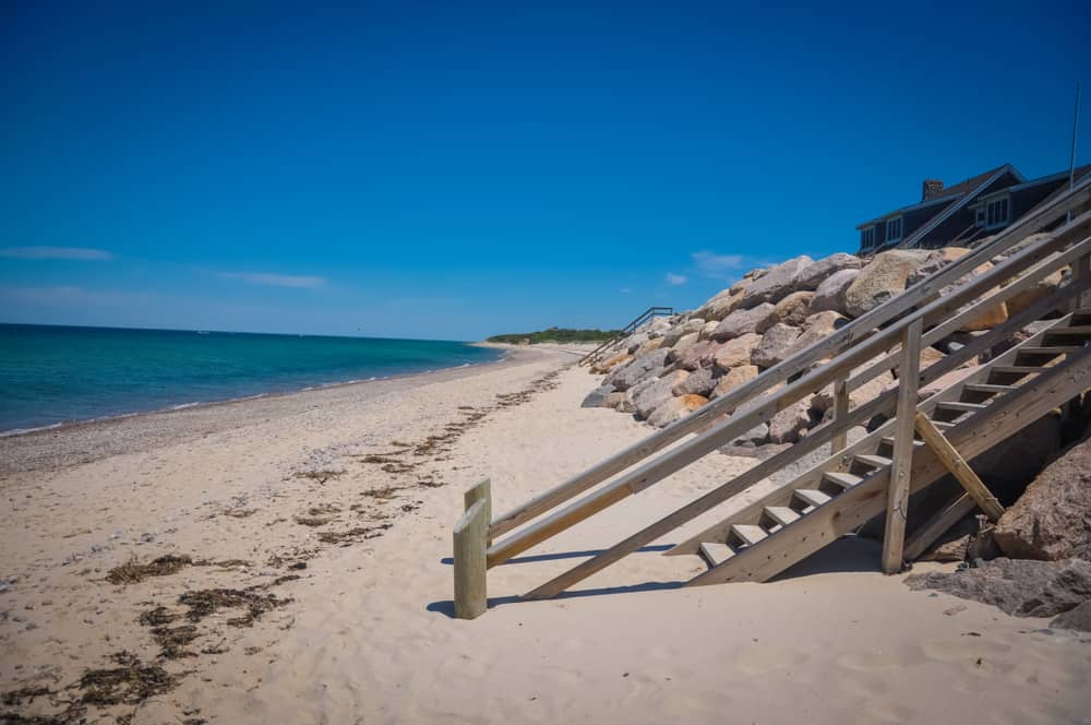 Wooden steps leading down to a sandy beach and a body of water