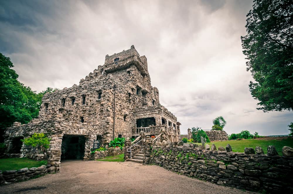A large stone castle and a stone wall seen on a cloudy day