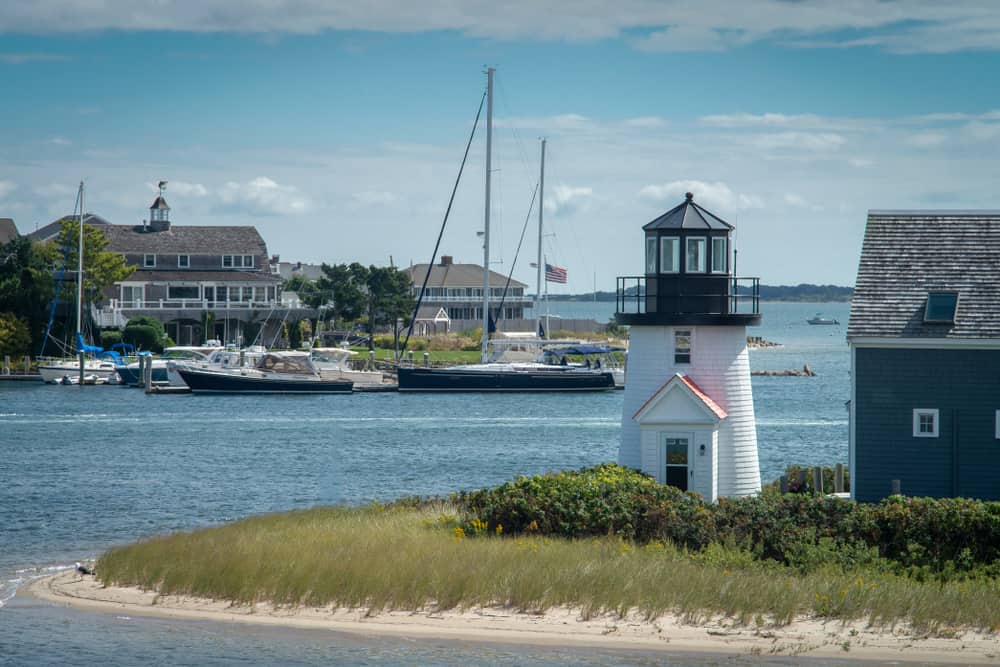 A lighthouse with boats in the water behind it 