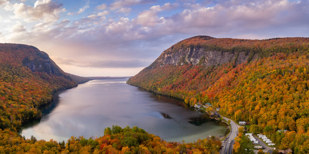 A body of water surrounded by mountains with autumn colored trees