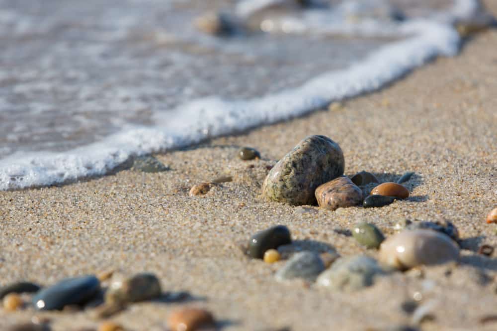 Rocks on the sand with a wave rolling in