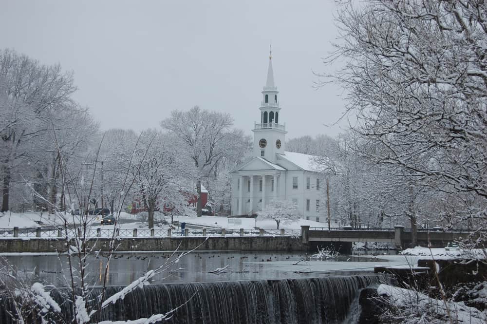 A picture of a white church with a steeple on a snowy day