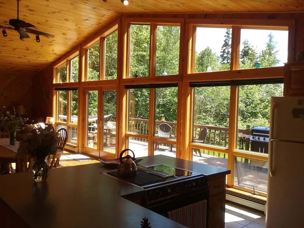 A room with a wall of windows looking out onto a wooden deck