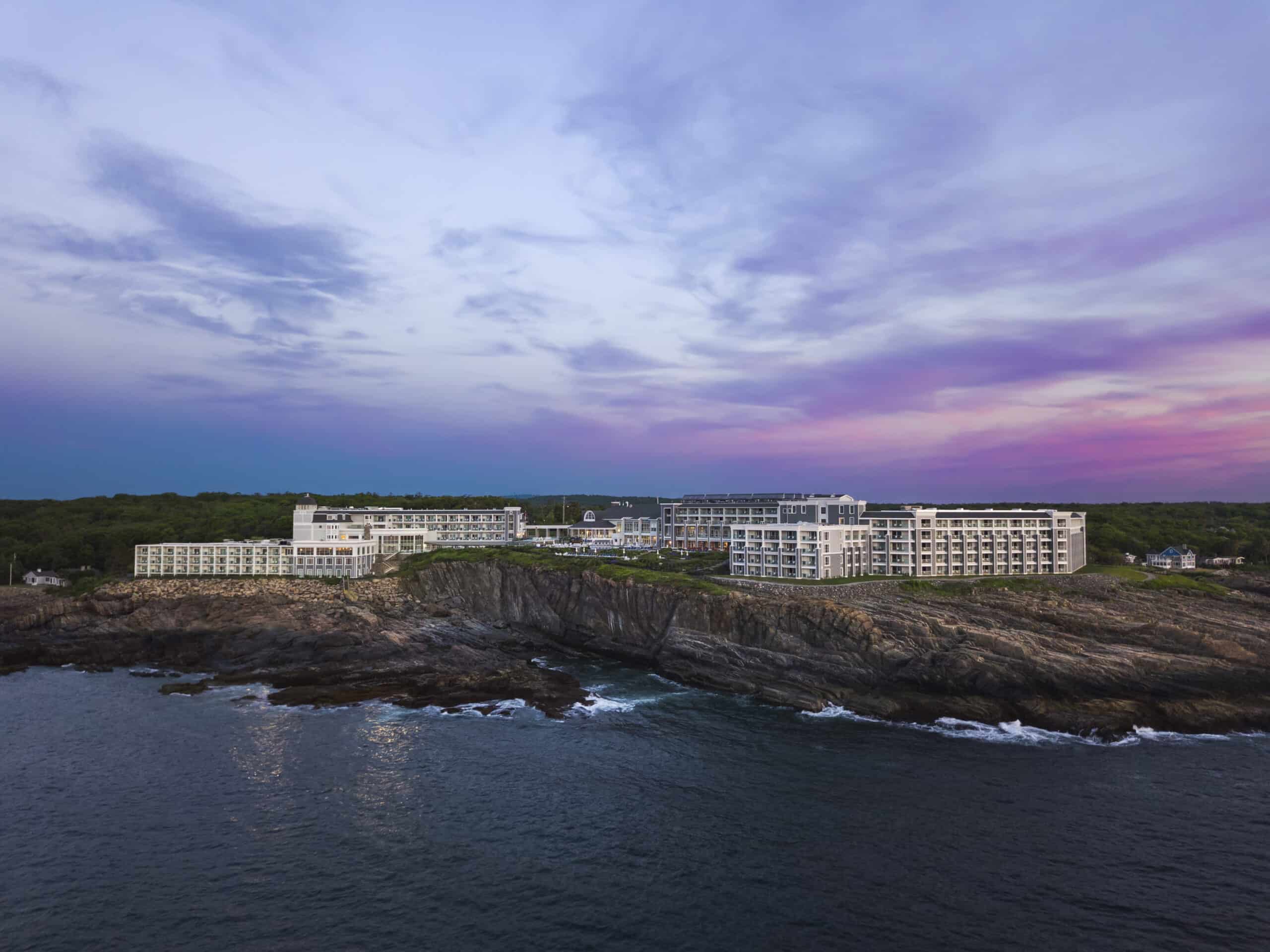 White hotel on the cliffs under a purple sunset