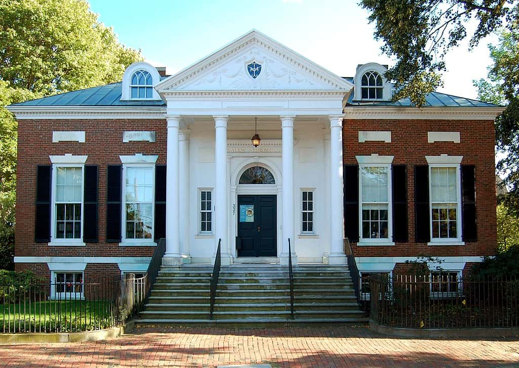 A brick building with white columns and stairs leading up to the front door