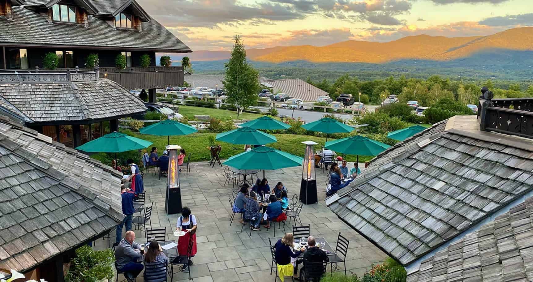 Customers eating at patio tables with green umbrellas over each table