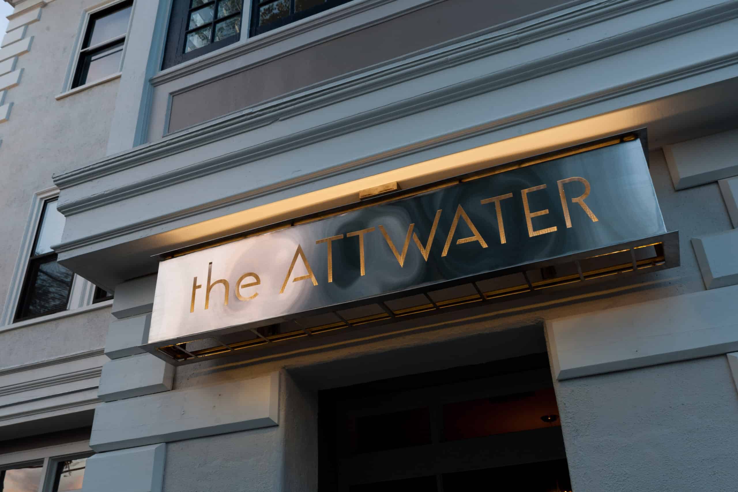 Closeup of a black sign with gold writing reading \"the Attwater\"