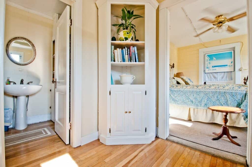 A white corner unit bookshelf with books and plants