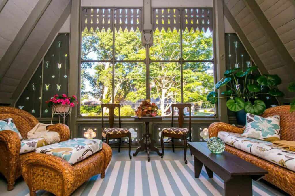 Two wicker sofas facing each other. In the back is a large picture window looking out into the trees