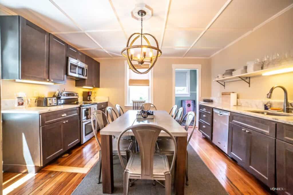 A modern kitchen with a long table and chairs in the center