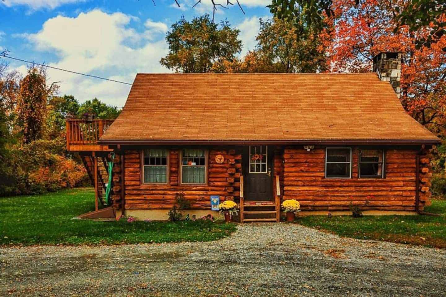 A log cabin with a gravel driveway out front. 