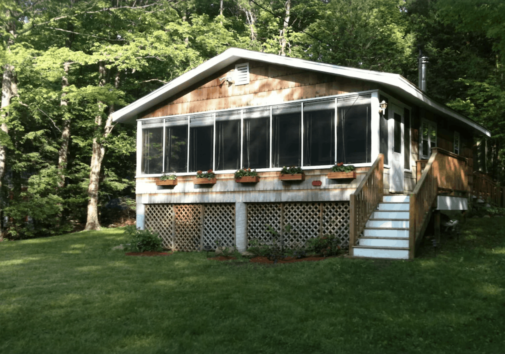 A Massachusetts vacation home with many windows and a flight of steps leading up to the main floor.