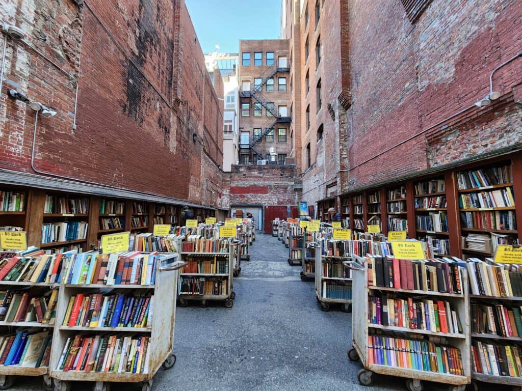 stacks of used books in a brick lined alleyway in boston: the iconic outdoor Brattle Book Shop